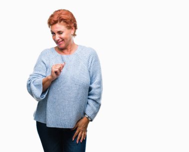 Seksi bir ifadeyle, neşeli ve mutlu yüzünü kameraya bakarak göz kırpıyor izole arka plan üzerinde kış kazak giyen Atrractive üst düzey beyaz Kızıl saçlı kadın.