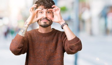 Parmaklarıyla, Uykulu ve sabah yorgunluk için yorgun gözlerini açmaya çalışırken izole arka plan üzerinde kış kazak giyen genç yakışıklı adam