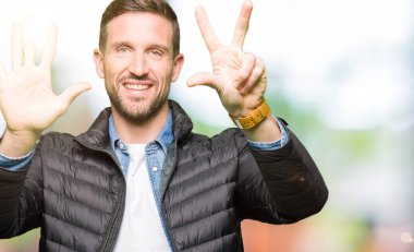 Kış ceket gösterme ve parmakları ile işaret giyen yakışıklı adam kendinden emin ve mutlu gülümseyerek süre sekiz numara.
