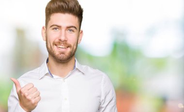 Genç yakışıklı iş adamı mutlu yaşasın el hareketini yapıyor. Başarı gösteren kameraya bakarak ifade onaylama.