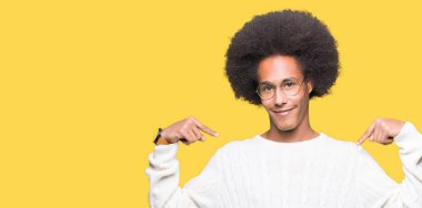 Yüzünde gülümseme ile kendinden emin görünüyorsun, kendini gururlu ve mutlu parmakları ile işaret gözlüklü afro saçlı genç Afro-Amerikan adam.
