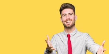 Genç yakışıklı iş adamı sarılmak için kollarını açarak gülümseyen kamera bakıyor. Neşeli ifade kucaklayan mutluluk.