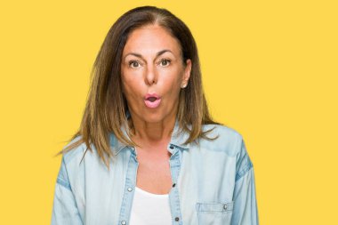 Orta yaş yetişkin kadın giyiyor rahat kot gömlek izole arka plan korkuyor ve şok sürpriz ifade ile üzerinde korku ve yüz heyecanlı.