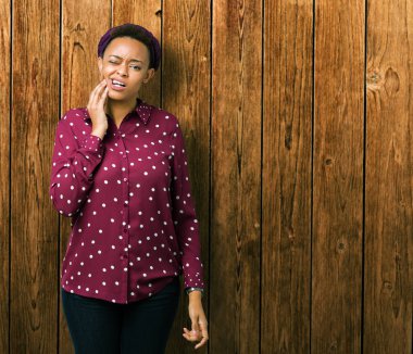 Üzerinde başörtüsü giyen güzel genç Afro-Amerikan kadın diş ağrısı veya dişlerde dişlerle ilgili hastalık nedeniyle ağız acı ifadesi ile el ile dokunmak arka plan izole. Diş hekimi kavramı.