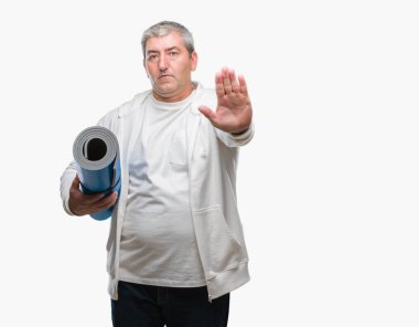 Üst düzey yakışıklı yoga mat açık eliyle dur işareti ile ciddi ve kendine güvenen ifade, savunma jest yapıyor izole arka plan üzerinde tutan