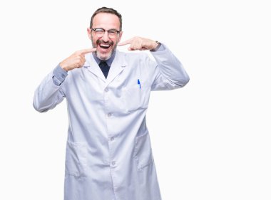 Kendinden emin gösterilen ve işaret parmakları diş ve ağız ile gülümseyen izole arka plan üzerinde beyaz önlük giyen orta yaş üst düzey ağarmış profesyonel adam. Sağlık kavramı.