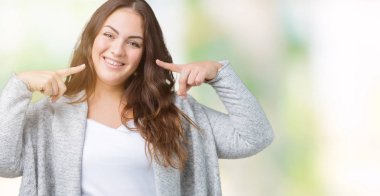 Artı boyutu genç kadın güzel kış ceket üzerinde arka plan emin gösterilen ve işaret parmakları diş ve ağız ile gülümseyen izole. Sağlık kavramı.