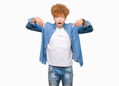 Afro saçlı kot giyen genç yakışıklı adam aşağı reklam, sürpriz yüz ve açık ağız gösterilen parmakları ile işaret ceket