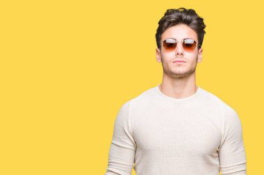 Genç yakışıklı adam yüzünde ciddi bir ifade ile izole arka plan üzerinde güneş gözlüğü takıyor. Basit ve doğal kameraya bakıyor.