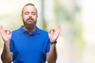 İzole arka plan üzerinde mavi gömlek giymiş genç beyaz hipster adam rahatla ve gülümseyen gözlerle kapalı parmak jestle meditasyon yapıyor. Yoga kavramı.