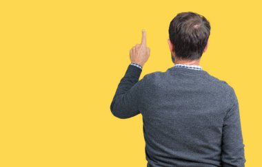 Bir kazak izole üzerinde giyen yakışıklı orta yaş üst düzey adam arka plan geriye doğru arkasında parmak eliyle işaret Posing