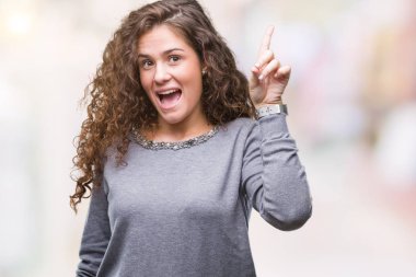 Güzel esmer kıvırcık saçlı Genç kız başarılı fikirle izole arka plan üzerinde işaret parmağı bir kazak giyiyor. Çıktıktan ve mutlu. Bir numara.