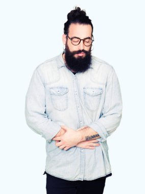 Genç hippi erkek uzun saç ve sakal el ile mide üzerinde çünkü gözlük ile bulantı, ağrılı hastalık hasta hissediyor. Ağrısı kavramı.