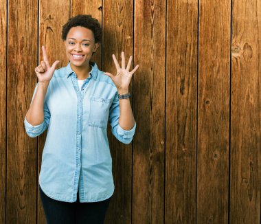 Gösterilen ve parmakları ile işaret izole arka plan üzerinde genç güzel bir Afrikalı-Amerikalı kadın kendinden emin ve mutlu gülümseyerek süre yedi numara.