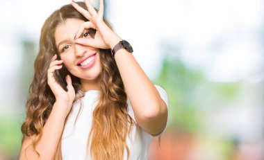 Mutlu yüz el parmaklarının arasından seyir göz üzerinde ok işaretiyle yapıyor gülümseyen ile telefonda alarak Genç Yetişkin kadın