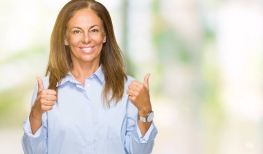 Güzel orta yaş iş yetişkin kadın el ile pozitif jest yapıyor izole arka plan başarı işareti yüzünden başparmak gülümseyen ve mutlu. Neşeli bir ifadeyle, kazanan jest kameraya bakıyor.