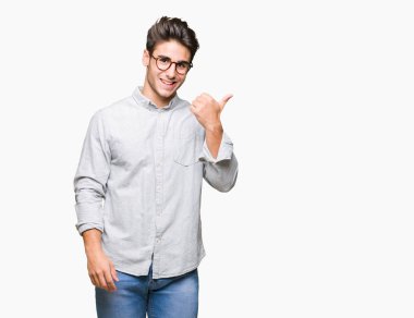 Seyir ve başparmak yanında yukarıyı mutlu yüz ile gülümseyen izole arka plan üzerinde gözlük takan genç yakışıklı adam.