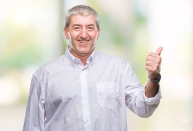 Seyir ve başparmak yanında yukarıyı mutlu yüz ile gülümseyen izole arka plan üzerinde üst düzey yakışıklı.