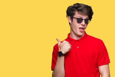 Genç yakışıklı adam hareketi el ile mutlu yaşasın yapıyor izole arka plan üzerinde güneş gözlüğü takıyor. Kameraya bakarak başarı gösteren ile ifade onaylama.