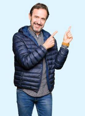 Orta yaş yakışıklı adam giyen kış ceket gülümseyen ve iki elleri ve parmakları ile tarafına işaret kamera bakıyor.