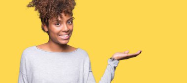 Neşeli sunulması ve kameraya bakarak avucunun ile işaret gülümseyen izole arka plan güzel genç Afro-Amerikan kadın.