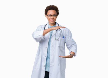 Üzerinde tıbbi ceket giyen genç Afro-Amerikan doktor kadın arka plan ile büyük ve büyük boy işaret, ölçü birimi sembol gösteren el eller izole. Kameraya bakarak gülümsüyordu. Ölçüm kavramı.