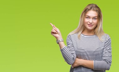 Kameraya bakarak yan el ve parmak ile işaret izole arka yüzünde kocaman bir gülümseme ile genç beyaz kadın.