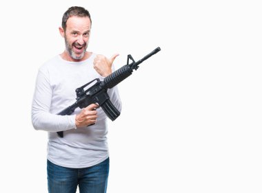 Orta yaş üst düzey ağarmış suç adam silahı işaret ve başparmak kadar mutlu yüz gülümseyen tarafı ile gösteren izole arka plan üzerinde'nın elinde