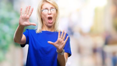 Şokta bağırarak korkuyor ve dehşet korku ifade dur hareketi el ile ile izole arka plan üzerinde gözlük takan genç güzel sarışın kadın. Panik kavramı.