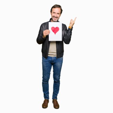 Kağıt kırmızı kalp ile çok mutlu el ve parmak ile tarafına işaret tutan yakışıklı orta yaş erkek