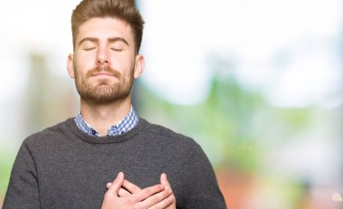 Göğüs Kapalı gözlerle ellerinde ve yüzünde minnettar jest ile gülümseyen yakışıklı zarif delikanlı. Sağlık kavramı.