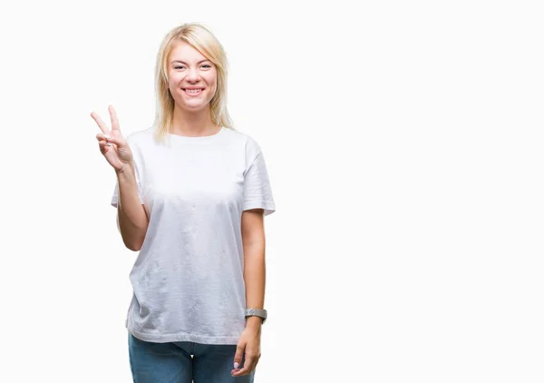 年轻美丽的金发碧眼的女人穿着白色的 T恤在孤立的背景显示和手指第二 同时微笑着自信和快乐 — 图库照片