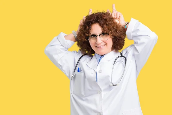 Middle ager senior doctor woman over isolated background Posing funny and crazy with fingers on head as bunny ears, smiling cheerful