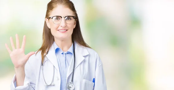 中年成熟的医生妇女穿着医疗外套在孤立的背景显示和手指指向五 同时微笑着自信和快乐 — 图库照片