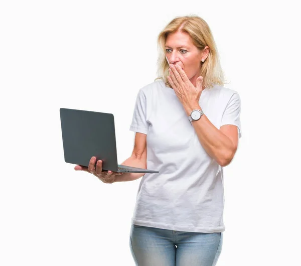 中年金发女人使用电脑笔记本电脑在孤立的背景下捂着嘴 手里拿着羞愧的错误 恐惧的表情 默默的害怕 秘密的概念 — 图库照片