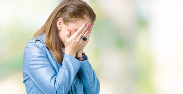 Beautiful middle age mature woman wearing fashion leather jacket over isolated background with sad expression covering face with hands while crying. Depression concept.