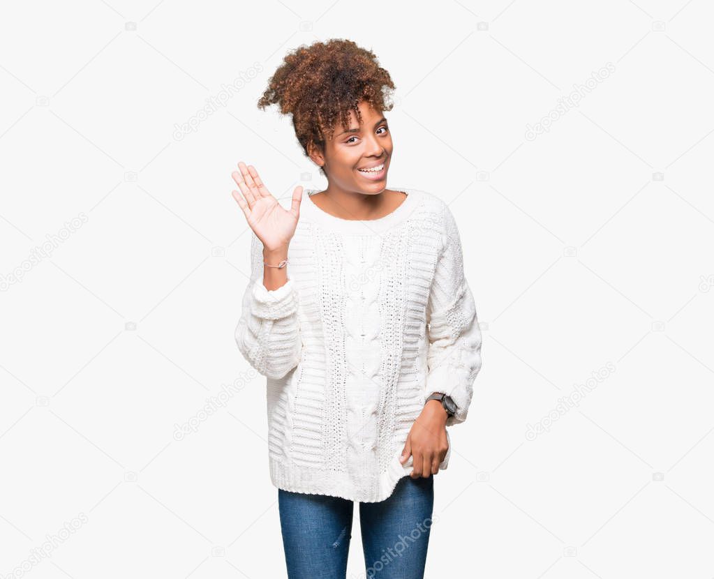 Beautiful young african american woman wearing winter sweater over isolated background Waiving saying hello happy and smiling, friendly welcome gesture