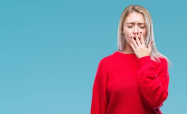 İzole arka plan üzerinde esneme sıkılmış kış kazak giyen genç sarışın kadın kapsayan ağız el ile yorgun. Restless ve uyku hali.