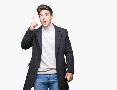 Genç zarif adam başarılı fikirle izole arka plan işaret parmağı üzerinde kış palto giyiyor. Çıktıktan ve mutlu. Bir numara.