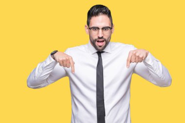 Genç yakışıklı iş adam gözlük izole üzerinde işaretleme aşağı reklam, sürpriz yüz ve açık ağız gösterilen parmakları ile arka plan