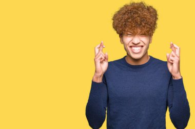 Umut ve gözleri kapalı geçiş parmaklarıyla gülümseyen afro saçlı genç yakışıklı adam. Şans ve batıl kavramı.