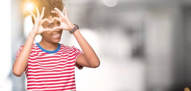 İzole arka plan yaparken kalp şekli ile el ve parmak işareti seyir gülümseyen güzel genç Afro-Amerikan kadın