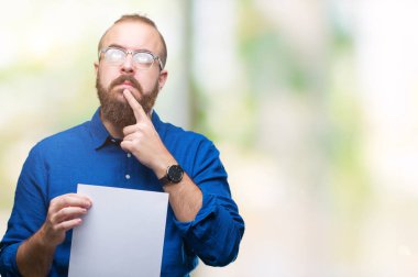 Gözlük takan ve boş kağıt tutan genç hipster adam arka plan ciddi bir yüz düşünme hakkında soru, çok karışık fikir izole