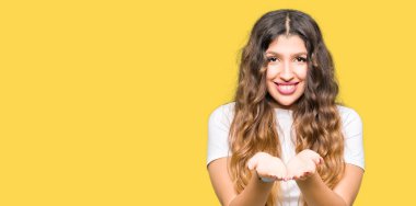 Casual beyaz t-shirt gülen birlikte alma veya jest veren el avuç içi ile giyen genç güzel kadın. Ayrı tutma ve koruma