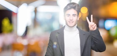 Gösterilen arka plan üzerinde kış ceket giyen genç zarif adam izole ve parmakları ile işaret kendinden emin ve mutlu gülümseyerek ise ikinci.