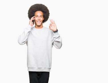 Parmak, mükemmel sembolü ile ok işareti yapıyor smartphone cep telefonu ile konuşurken afro saçlı genç Afro-Amerikan adam