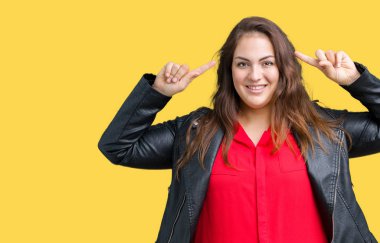 Artı boyutu genç kadın izole arka plan üzerinde bir moda deri ceket giymiş güzel her ikisi ile baş gösteren gülen eller parmak, harika bir fikir ya da düşünce, iyi hafıza