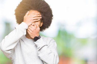 Sportif kazak kapsayan gözler ve ağız el ile giyen afro saçlı genç Afro-Amerikan adam şaşırttı ve şok. Duygu gizleme