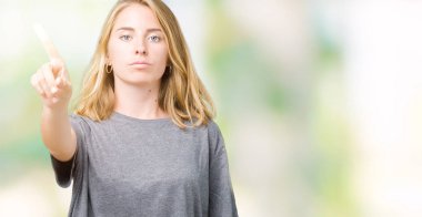 Büyük boy rahat t-shirt üzerinde izole giyen güzel genç kadın arka plan işaret parmağını ve kızgın ifade ile