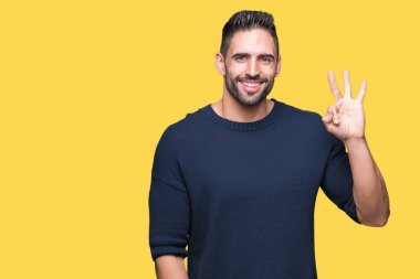 Gösterilen arka plan üzerinde kazak giyen genç yakışıklı adam izole ve parmakları ile işaret üçüncü gülümseyen ise kendinden emin ve mutlu.